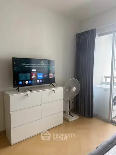 Modern living room with TV, dresser, and balcony access in a stylish apartment.