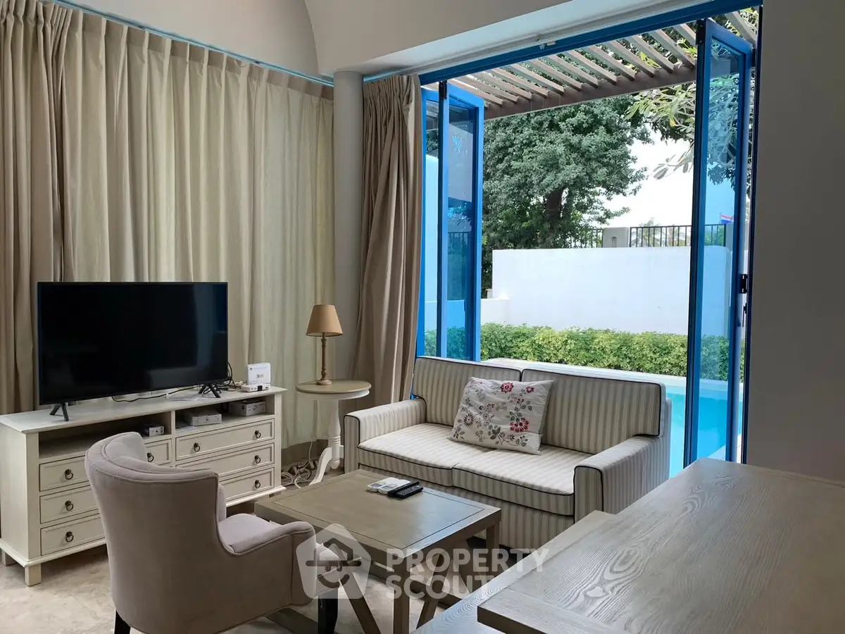 Charming living room with pool view, elegant furniture, and natural light.