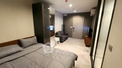 Modern studio apartment with cozy bedroom and living area, featuring sleek furniture and neutral tones.