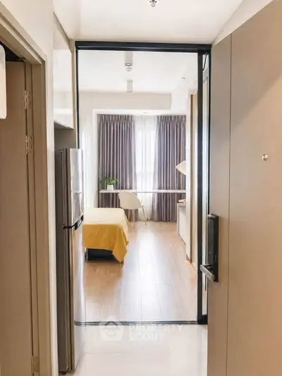 Modern apartment entrance leading to a cozy bedroom with natural light and stylish decor.
