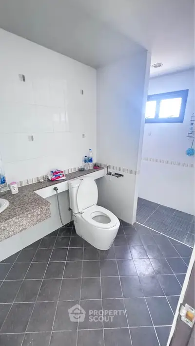 Modern bathroom with sleek design and tiled flooring, featuring a toilet and spacious shower area.