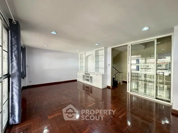 Spacious living room with hardwood floors and large windows in modern apartment.
