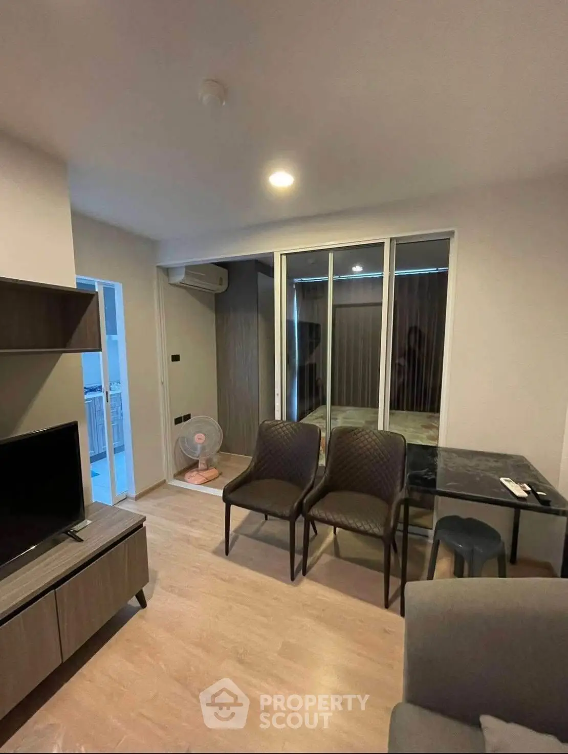 Modern living room with sleek furniture and open layout, featuring a TV and dining area.