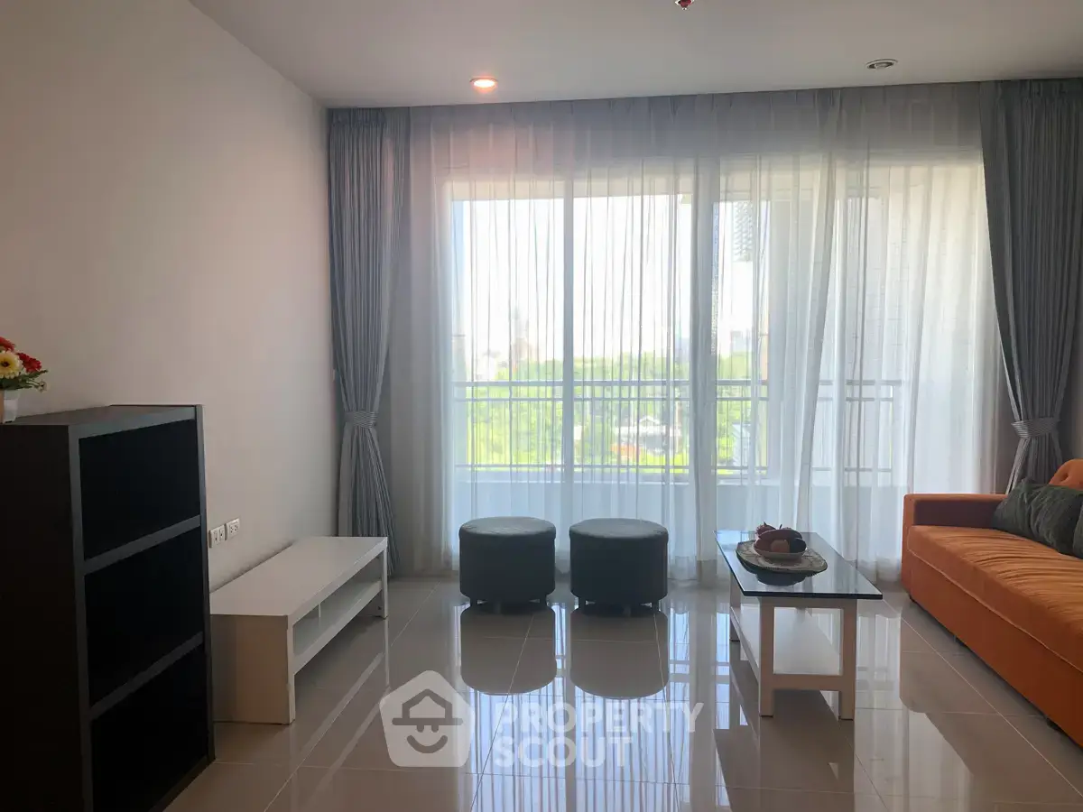 Spacious living room with modern decor and large windows offering natural light and a view.
