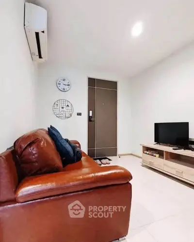 Cozy living room with leather sofa, wall-mounted air conditioner, and modern TV setup.