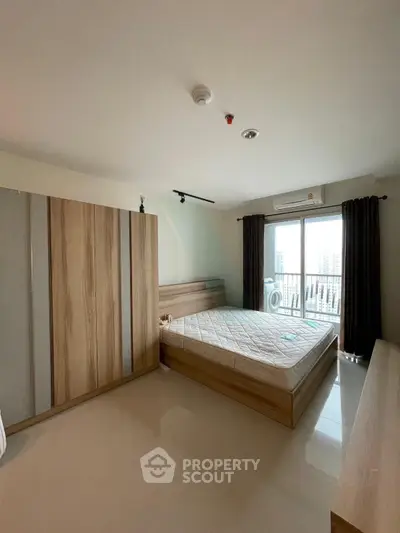 Spacious bedroom with large window and modern furnishings in a high-rise apartment.