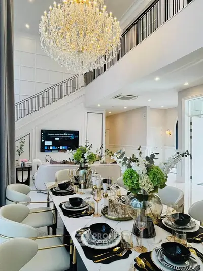 Luxurious dining room with elegant chandelier and modern decor in a spacious open-plan living area.