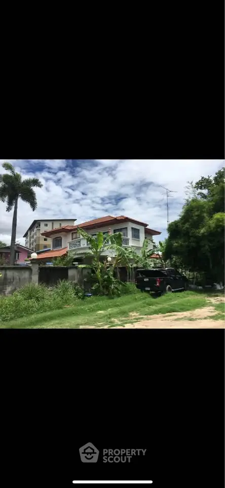 Charming two-story house with lush garden and palm trees, perfect for serene living.