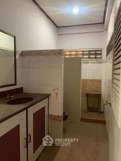Cozy bathroom with tiled walls and built-in sink, perfect for a compact home.