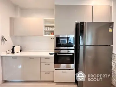 Modern kitchen with sleek cabinets, built-in oven, and stainless steel fridge