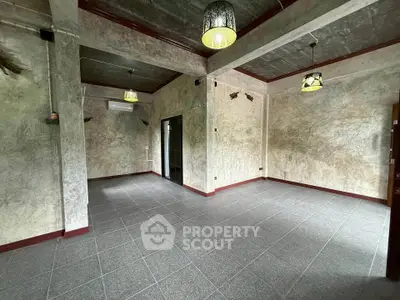 Spacious industrial-style room with modern lighting and tiled flooring