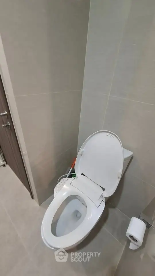 Modern bathroom with sleek toilet and neutral tiles, perfect for a contemporary home.