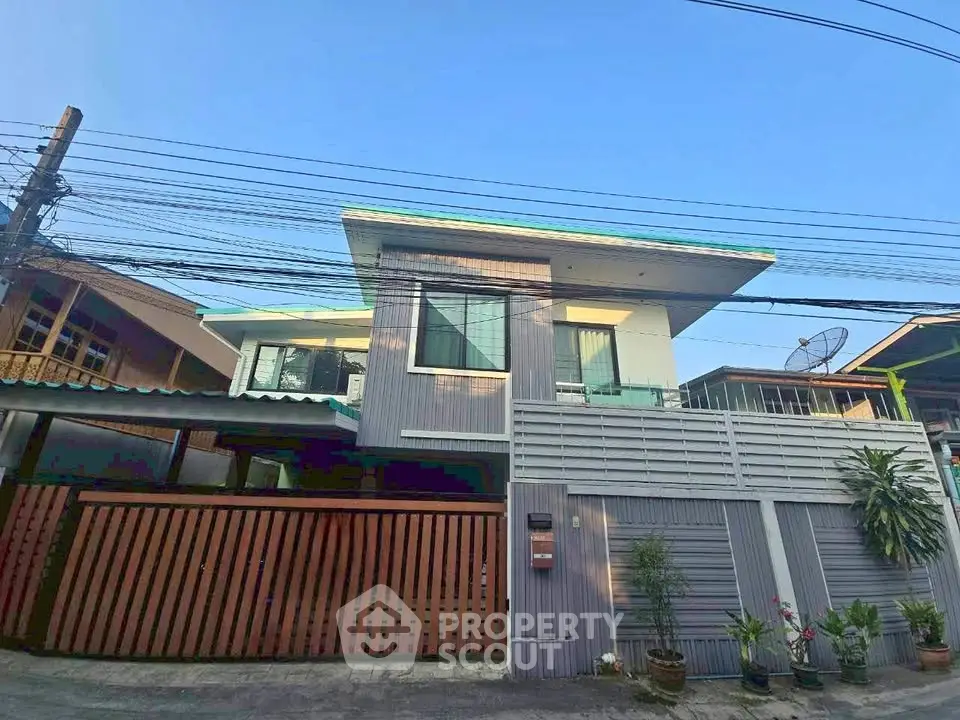 Modern two-story house with sleek design and gated entrance in a suburban neighborhood.