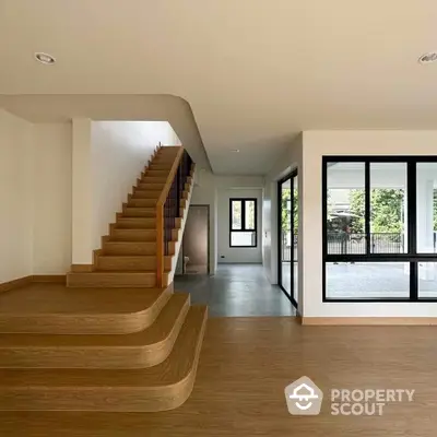 Modern interior with wooden staircase and large windows offering natural light