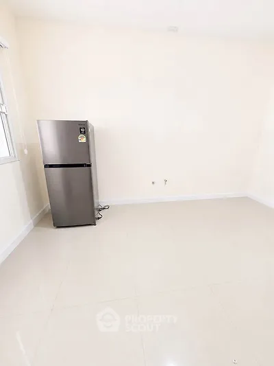 Spacious empty room with sleek stainless steel refrigerator, ideal for modern kitchen setup.