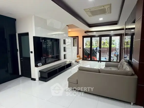 Spacious modern living room with sleek design and large windows opening to a garden view.