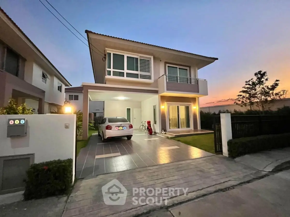 Modern two-story house with carport and landscaped garden at sunset