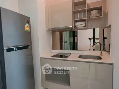 Modern compact kitchen with sleek cabinetry and stainless steel appliances in a stylish apartment.