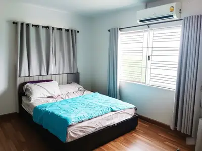 Cozy bedroom with modern decor and natural light, featuring a comfortable bed and air conditioning.