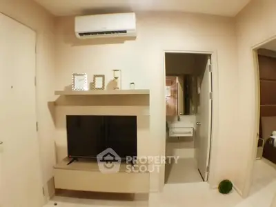 Modern living room with TV and air conditioning, adjacent to a bathroom, showcasing sleek interior design.