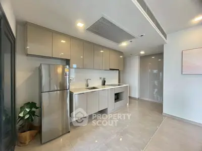 Modern kitchen with sleek cabinets and stainless steel fridge in a spacious apartment.