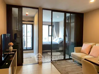 Modern apartment with glass sliding doors separating living room and bedroom, stylish decor.