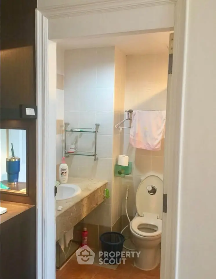 Compact bathroom with modern fixtures and tiled walls, featuring a sink and toilet.