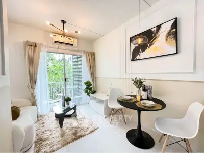 Modern living room with stylish decor, cozy seating, and a view of lush greenery through large windows.