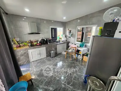 Modern kitchen with sleek marble flooring and stainless steel appliances in a contemporary home.