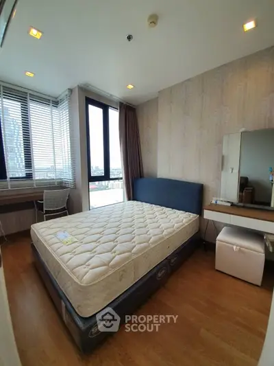 Modern bedroom with large window and city view, featuring a comfortable bed and stylish decor.