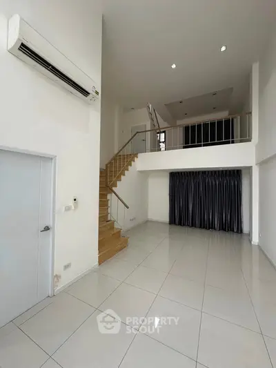 Spacious modern duplex with high ceilings and sleek staircase