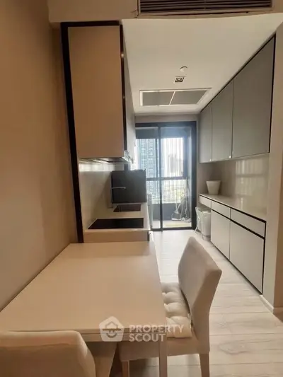 Modern kitchen with sleek cabinetry and dining area in high-rise apartment