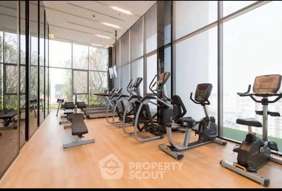Modern gym with state-of-the-art equipment and floor-to-ceiling windows in luxury building.