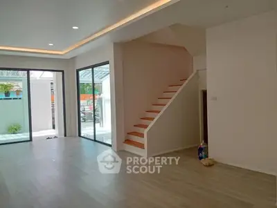 Spacious modern living room with large windows and staircase, ideal for family gatherings.