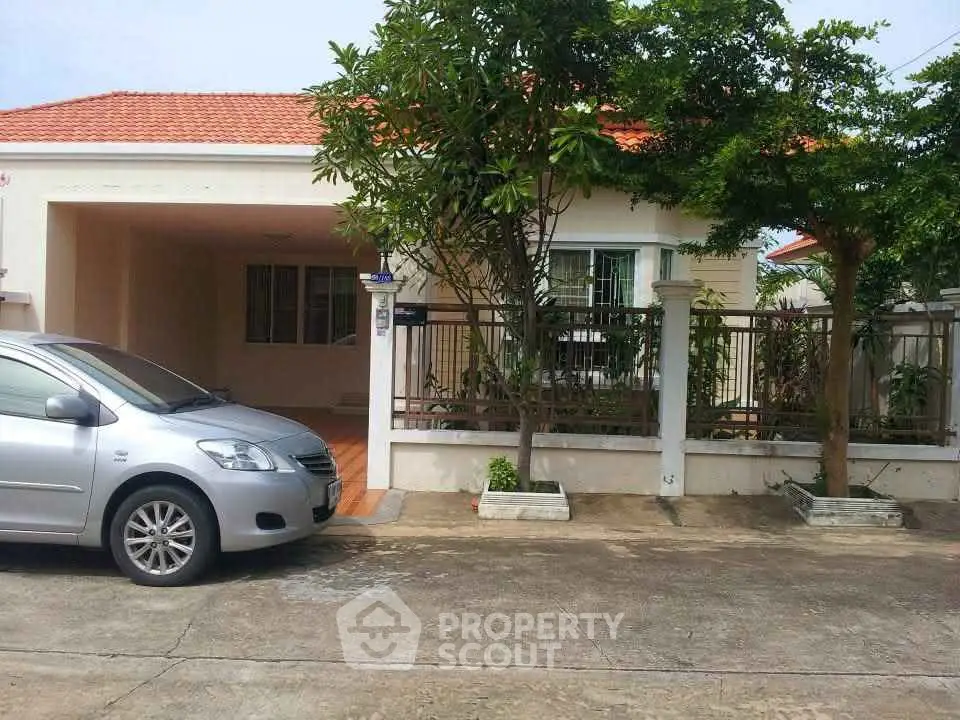 Charming single-story house with carport and lush greenery in a serene neighborhood.