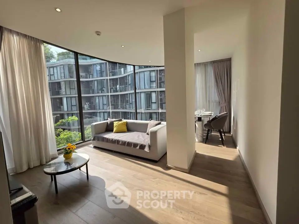Modern living room with floor-to-ceiling windows and stylish furniture, offering a stunning view of contemporary architecture.