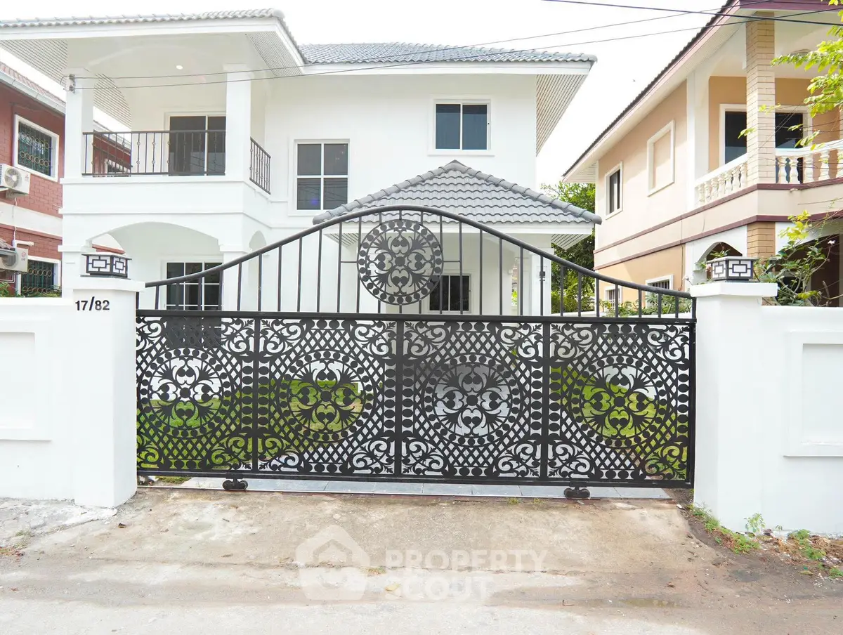 Elegant white house with ornate wrought iron gate and lush greenery