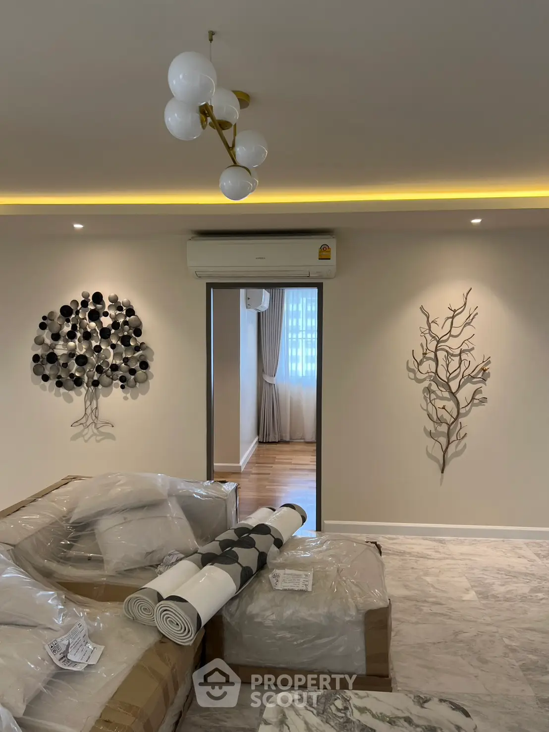 Modern living room with elegant decor and stylish lighting, featuring a glimpse into a cozy bedroom.