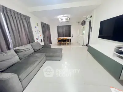 Spacious modern living room with sleek furniture and large TV, perfect for family gatherings.
