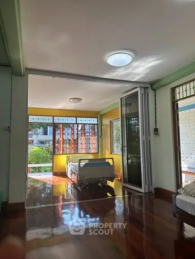 Spacious room with wooden flooring and large windows offering natural light and garden view.