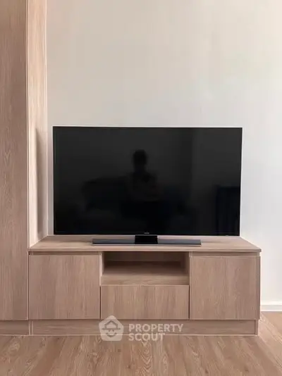 Modern living room with sleek wooden TV stand and large flat-screen TV, perfect for entertainment.