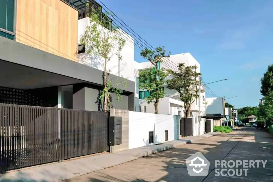 Modern residential building with sleek design and lush greenery in a serene neighborhood setting.