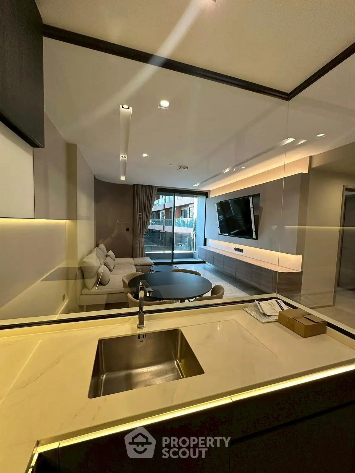 Modern open-layout living room with sleek kitchen view and large TV setup