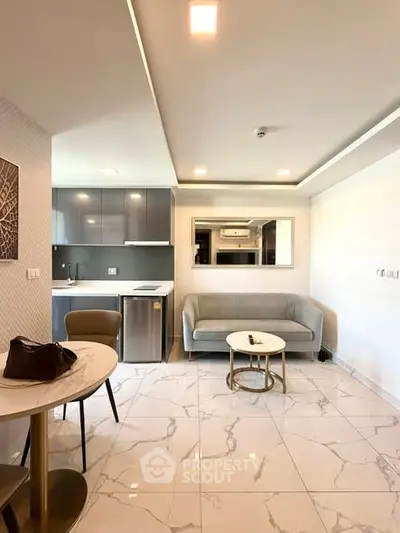 Modern open-plan living room with sleek kitchen and elegant marble flooring.