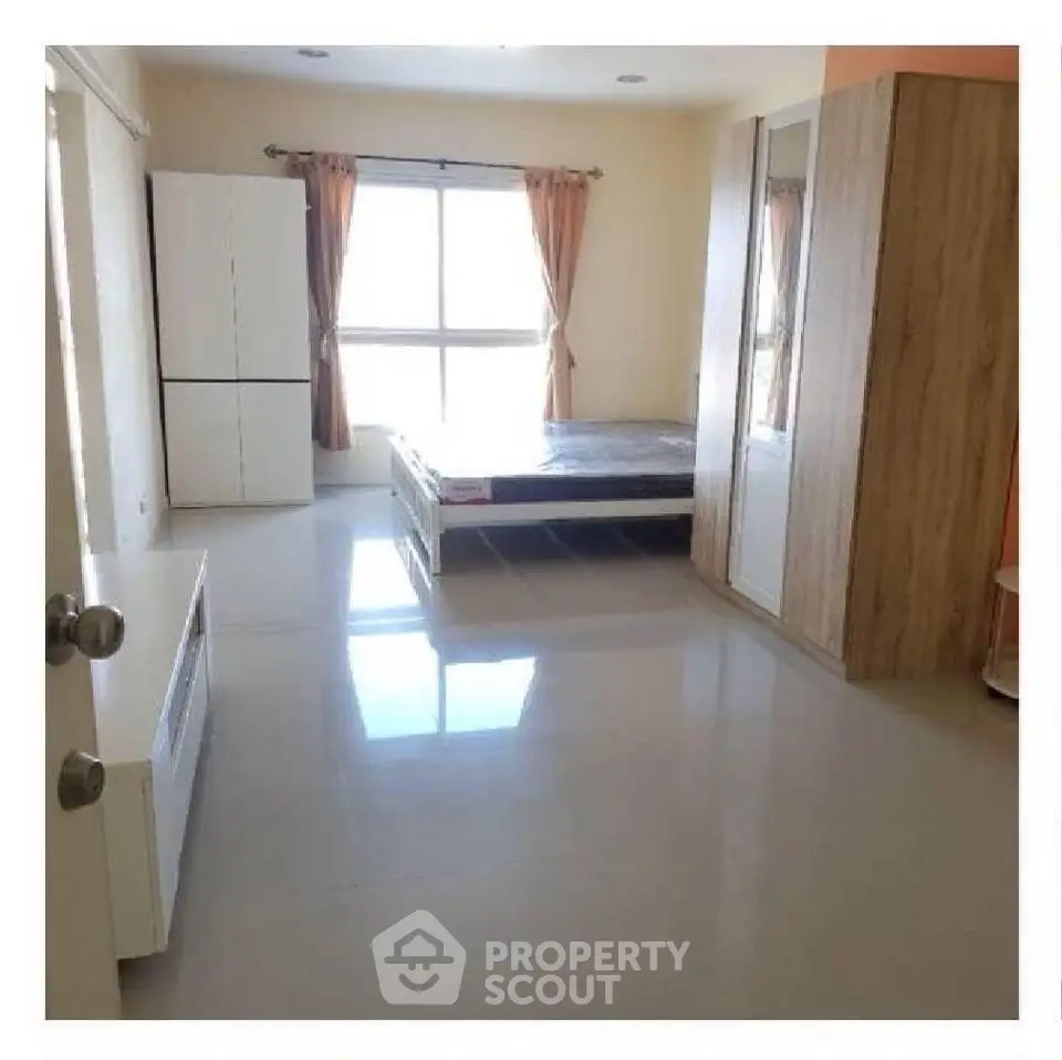 Spacious bedroom with large window and modern furnishings in a bright apartment.