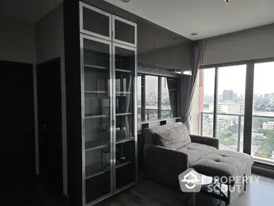 Modern living room with city view, featuring sleek glass cabinet and cozy seating area.