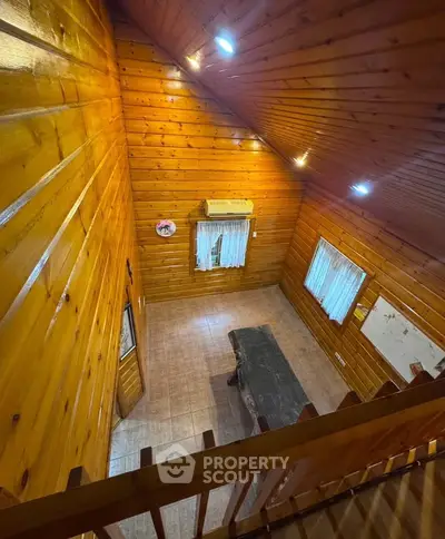 Charming wooden interior with high ceiling and rustic decor, perfect for cozy living.