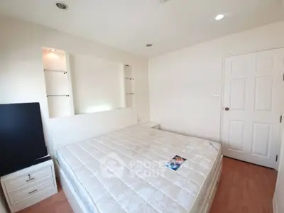 Spacious bedroom with ample natural light, featuring a large bed, built-in shelving, and modern flooring, ideal for restful living.
