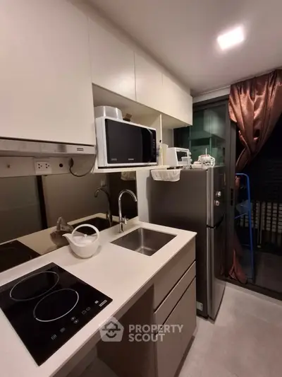 Modern compact kitchen with sleek appliances and balcony access