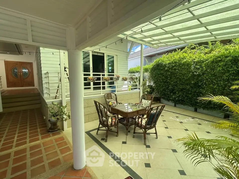 Charming covered patio with elegant outdoor dining set and lush greenery, perfect for relaxation and entertaining.